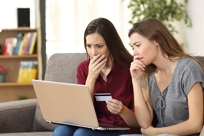 Two women with worried looks viewing laptop computer