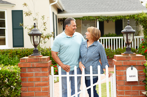 Smiling couple standing outside home