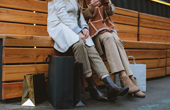 two people sitting and talking with shopping bags on the ground