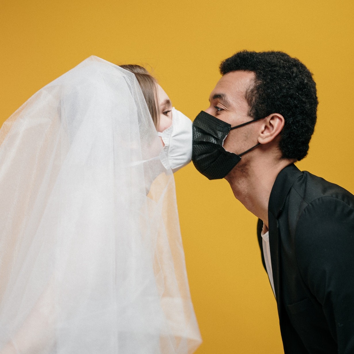 Braide and groom kissing with masks on